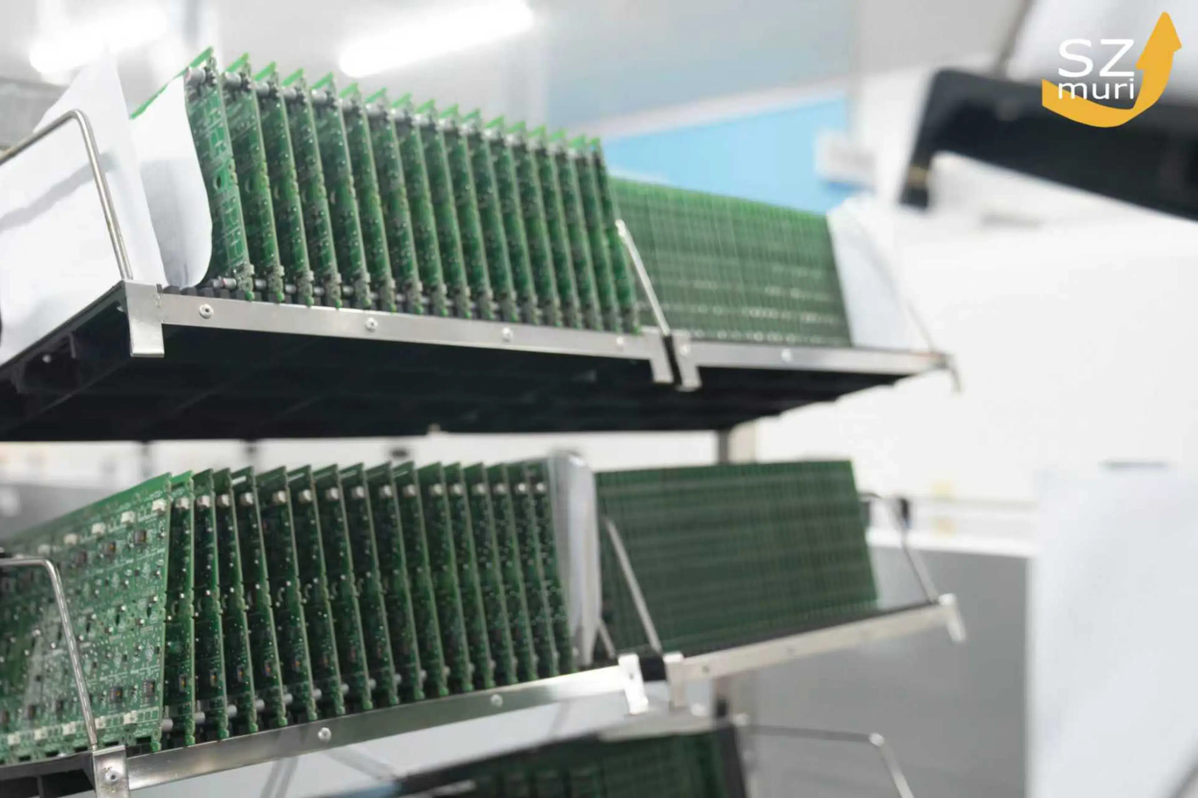 Zahlreiche grüne Leiterplatten in silbernen Halterungen in heller Fabrikumgebung