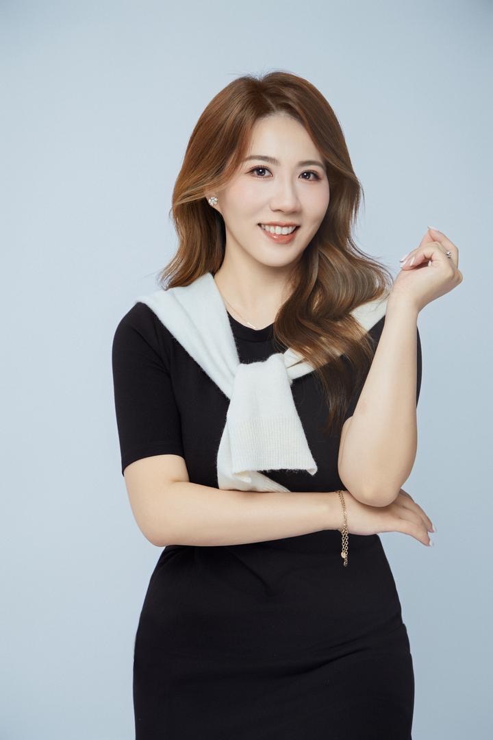 Frau mit langen braunen Haaren lächelt freundlich und trägt ein schwarzes Kleid mit weißem Schal