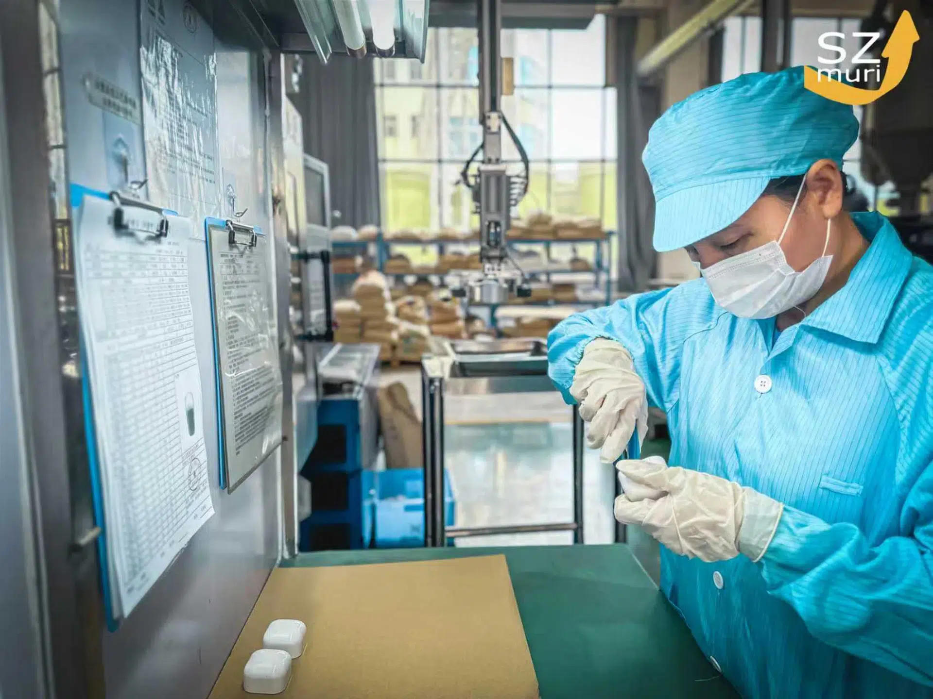 Eine Person im blauen Kittel und Mundschutz arbeitet konzentriert in einer Fabrik